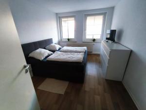 a small bedroom with a bed and two windows at Business Apartment Chemnitz in Chemnitz