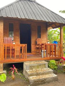 Ce chalet en bois dispose d'une terrasse couverte et d'une table. dans l'établissement Sejooq Cottages, à Tetebatu
