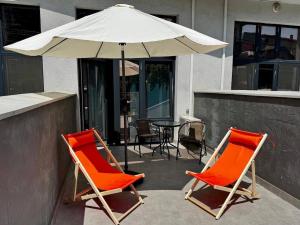 敖德萨Апартаменти Аркадія, з терасою та 3 хв до моря的露台上的两把橙色椅子和一把遮阳伞