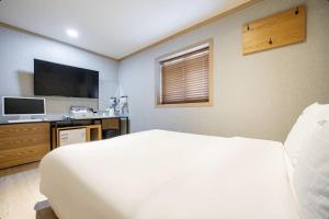 a bedroom with a bed and a flat screen tv at Yeosu 25 Motel in Yeosu