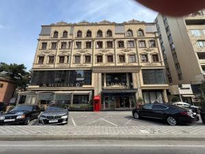 a large building with cars parked in a parking lot at Adisson Hotel Baku in Azadliq avenue in Baku