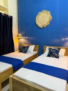 zwei Betten in einem Zimmer mit einer blauen Wand in der Unterkunft Golden Nap hostel in Zanzibar City