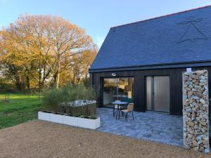 Ce cottage noir dispose d'une terrasse et d'une table. dans l'établissement Loft chic avec Jacuzzi, à Plumergat