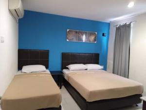 two beds in a room with a blue wall at Vitro Hotel in Johor Bahru