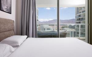une chambre avec un lit blanc et une grande fenêtre dans l'établissement Eilat 42-by rently, à Eilat 55 autres photos