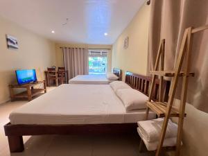 a bedroom with two beds and a tv in it at Boracay Amor Apartment (Garden) in Boracay