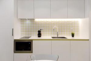 eine Küche mit weißen Schränken und einer Spüle in der Unterkunft T1 Moliceiros Centro de Aveiro in Aveiro + 20 Fotos