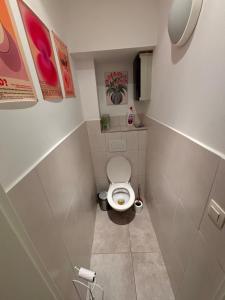 Un pequeño baño con inodoro y cuadros en las paredes. en flatwatermael, en Bruselas