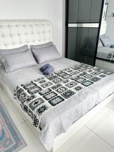 - un lit blanc avec une couette et des oreillers en noir et blanc dans l'établissement Stay & Rest - The Luxe Lodge, à Klang