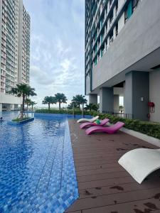 - une piscine avec des chaises longues roses à côté d'un bâtiment dans l'établissement Stay & Rest - The Luxe Lodge, à Klang