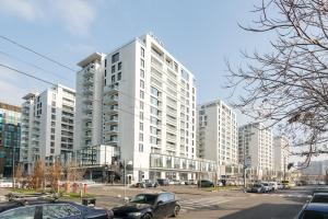 Central ONE Comfort plus Parking في بوخارست: مبنى أبيض كبير تصطف السيارات أمامه