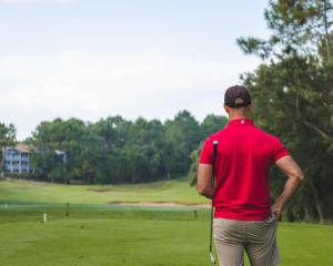 a man in a red shirt standing on a golf course at Charmant T2 centre Capbreton in Capbreton