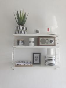 a white shelf with a plant on a wall at Charmant T2 centre Capbreton in Capbreton