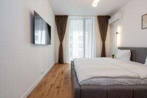 Central ONE Comfort plus Parking في بوخارست: غرفة نوم بسرير وتلفزيون على جدار