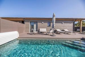 einem Pool mit Stühlen und einem Sonnenschirm neben einem Haus in der Unterkunft Résidence Pierre & Vacances Premium Vesna Rossa in Porto-Vecchio