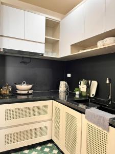 une cuisine avec des armoires blanches et des comptoirs noirs dans l'établissement Châu Giang Luxury -Nera Garden APartment 2-3 Bedroom, FREE hồ bơi, à Hue