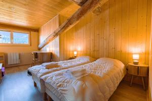 a bedroom with two beds in a wooden wall at L'Eco-logis du Clos Des Tilleuls in Molieres-Glaudaz