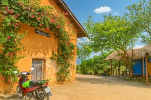 ハザンにあるDồn Dao Homestayの花の咲く建物の前に停められたオートバイ