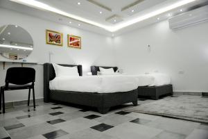 two beds in a room with a mirror and a chair at Rose In Apartment in Wadi Musa