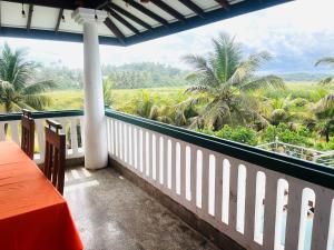 a balcony with a table and a view of palm trees at Island House Hiriketiya in Dickwella