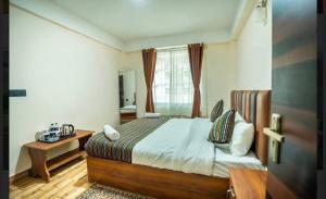 ein Schlafzimmer mit einem Bett und einem Fenster in der Unterkunft Padmashree Hotel & Spa in Darjeeling