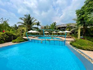 a large swimming pool with blue water and umbrellas at Vamxang Rustic Home in Can Tho