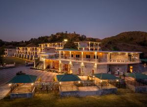a large building with green umbrellas in front of it at Jal Dhara Resort in Kumbhalgarh