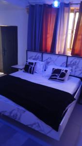 une chambre avec un grand lit avec des oreillers noirs et blancs dans l'établissement Guest Apartments, à New Weija