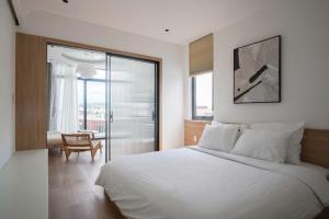 a bedroom with a white bed and a sliding glass door at Adory Homestay Huế in Hue