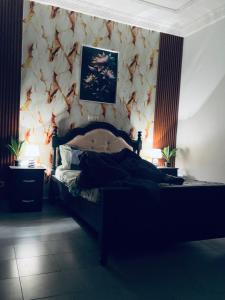 1 dormitorio con 1 cama con pared de flores en Appartement Brel, en Yaoundé