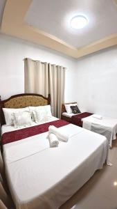 プエルト・プリンセサにあるCozy Stop Inn - Puerto Princesaの白いシーツが敷かれたホテルの部屋にベッドが2つある