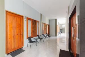 a hallway with chairs and wooden doors in a building at Urbanview Hotel Brodam's Pematang Siantar by RedDoorz in Pematangsiantar