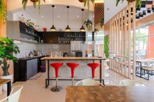 a kitchen with a bar with red stools at Urbanview Hotel Brodam's Pematang Siantar by RedDoorz in Pematangsiantar