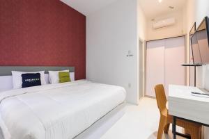 a bedroom with a white bed and a desk at Urbanview Hotel Brodam's Pematang Siantar by RedDoorz in Pematangsiantar