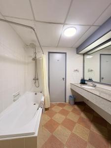 a bathroom with a tub and a sink and a mirror at Rainbow Paradise BeachFront Penang in Tanjung Bungah