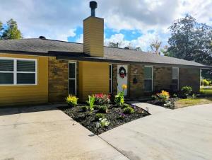 a yellow house with flowers in the driveway at The Denham Springs Esape- Pool, Comfort & Charm in Denham Springs +33 photos