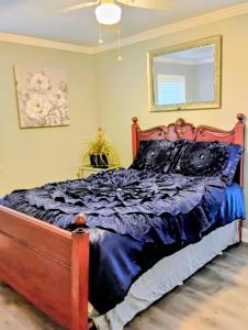 ein Schlafzimmer mit einem Bett mit einer blauen Bettdecke in der Unterkunft The Denham Springs Esape- Pool, Comfort & Charm in Denham Springs