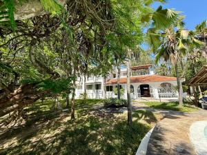 a large white house with trees in front of it at Sandbox in Kilifi
