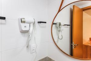 a hairdryer in a bathroom with a mirror at Studio Novo com ar ao lado da Igreja São Mateus in Juiz de Fora