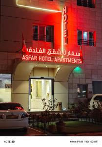a sign for an asian hotel with a car parked outside at Asfar Hotel Apartments in Muscat
