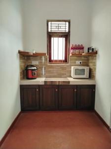 a kitchen with a counter with a microwave and a window at Bobbys Villa Mirissa Walk to Mirissa Beach in Mirissa