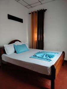 a bed in a room with blue pillows on it at Bobbys Villa Mirissa Walk to Mirissa Beach in Mirissa