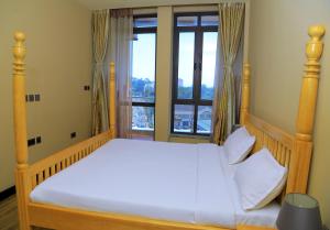 カンパラにあるThe Happy Nestの大きな窓のあるベッドのある寝室