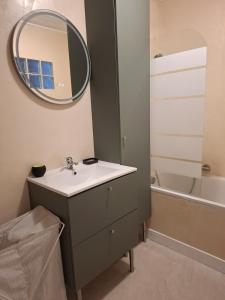 a bathroom with a sink and a mirror and a tub at Cozy Go in Rochefort
