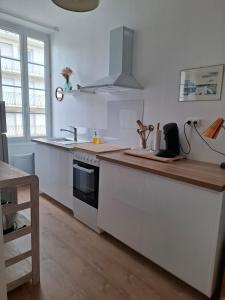 a kitchen with white cabinets and a wooden counter top at Cozy Go in Rochefort