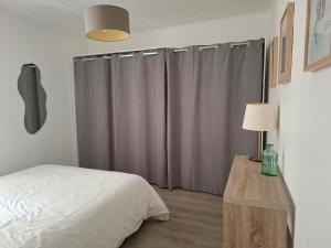 a bedroom with a bed and a table with a lamp at Cozy Go in Rochefort