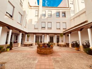 a large white building with a courtyard with benches at El rincón exquisito in Albacete