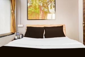 1 dormitorio con 1 cama con sábanas blancas y almohadas negras en Hotel O Elite Studio, en Kharadi