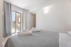 a white bedroom with a large bed with towels on it at Villa Serenella in Carovigno