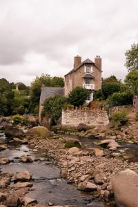 an old house on a hill next to a river at Logis Hôtel et Restaurant La Pension du Moulin in Pont-Aven